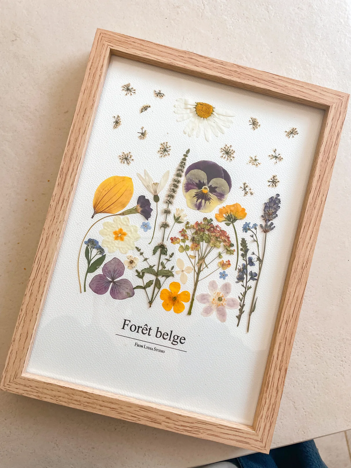 Composition botanique de fleurs et feuilles pressées dans un cadre en bois clair